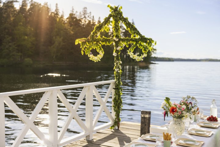 Midsommarstång och dukat bord vid vattnet