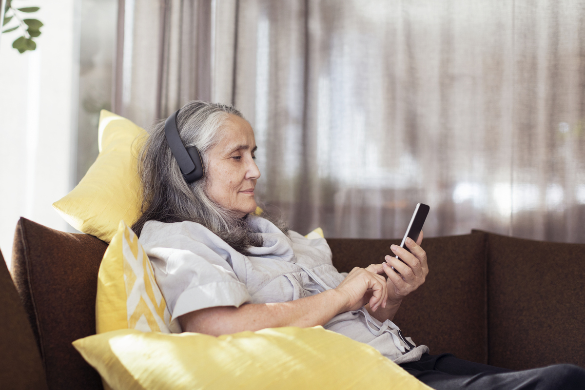 En kvinna sitter i en soffa med en mobiltelefon.