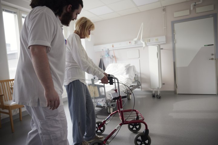 Vårdavdelning på sjukhus med personal, patient och rollator