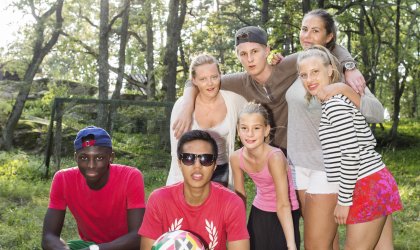 Ett gäng ungdomar med fotboll som tittar in i kameran och ler