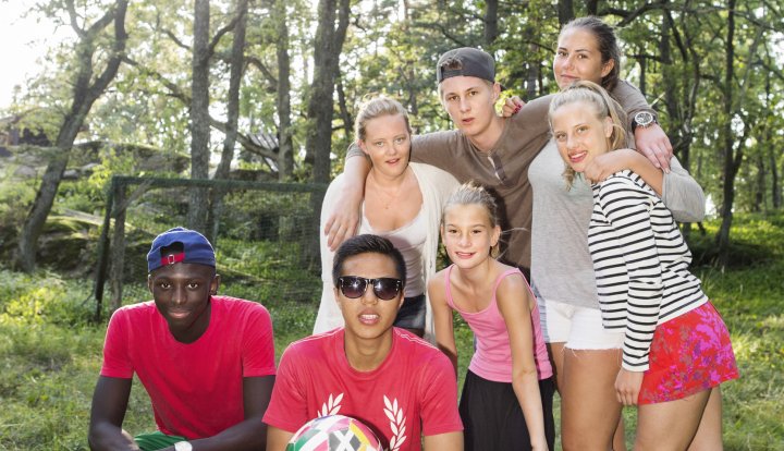 Ett gäng ungdomar med fotboll som tittar in i kameran och ler