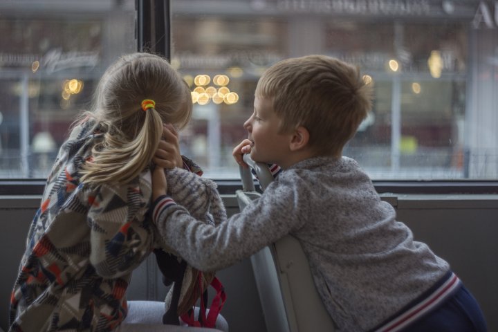 En flicka och en pojke sitter på en buss vända mot varandra
