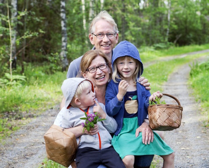 Glada mor eller farföräldrar med barnbarn i skogen.