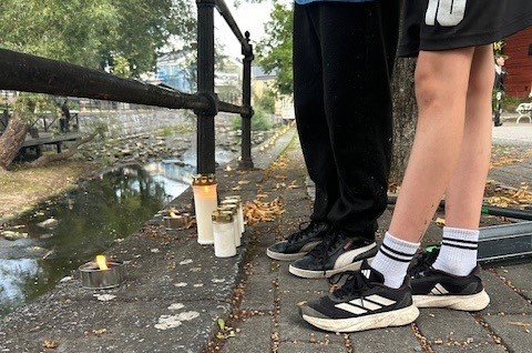 Tända ljus ute vid Norrtäljeån, pojkar står bredvid ljusen