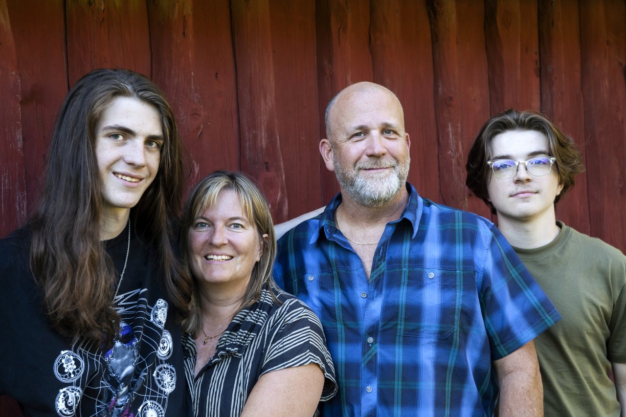 Familjebildporträtt mot röd barkgrund.