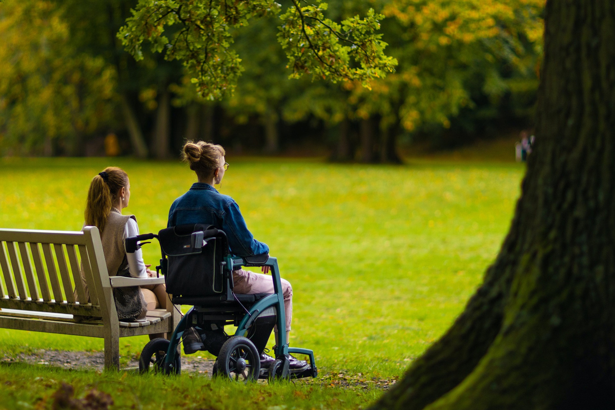 En kvinna i rullstol och en kvinna som sitter på en bänk