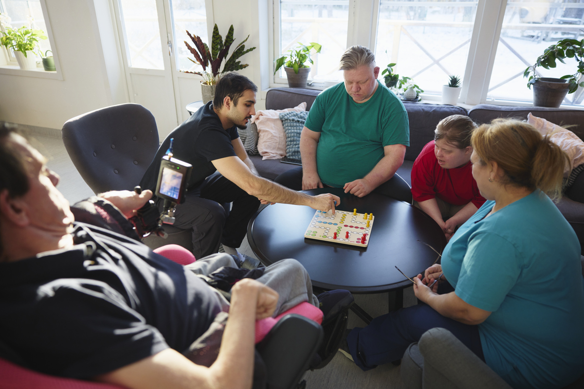 Brukare och personal spelar spel tillsammans på ett Vård och omsorgsboende LSS