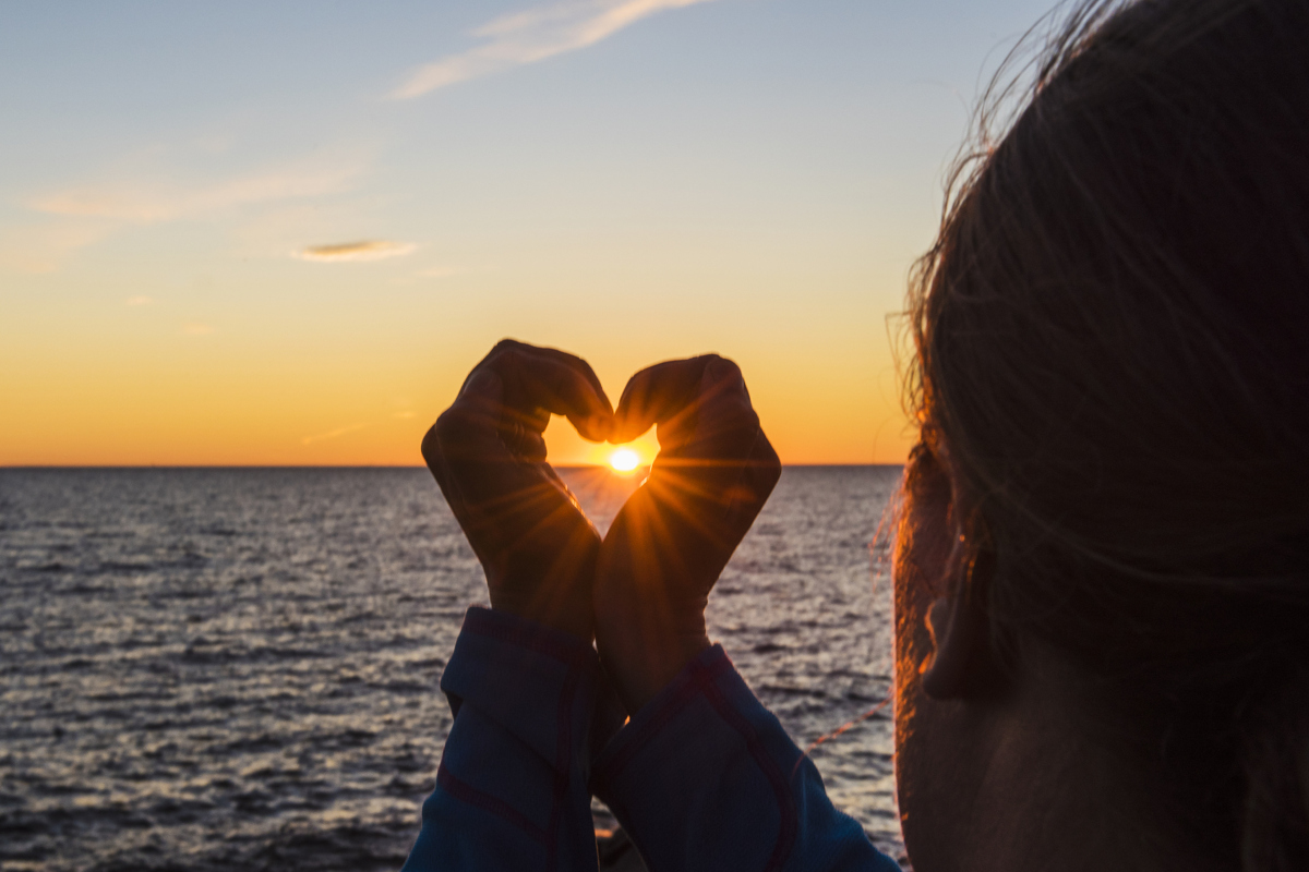 En person som håller ett hjärtformat föremål framför havet